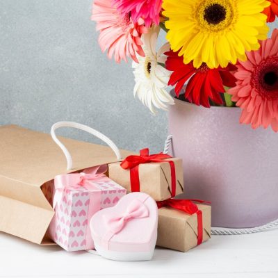 bucket-with-gerbera-flowers-gift-papers-boxes_23-2148268290